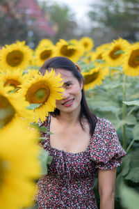 Portrait of young woman standing against yellow flower