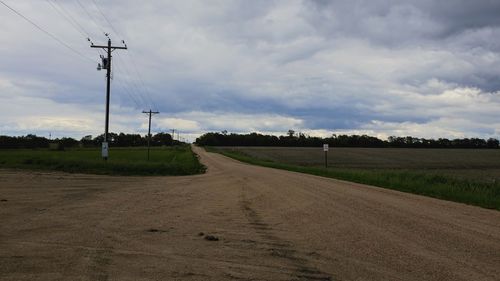 Road amidst field against sky