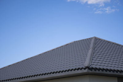 Low angle view of building roof against clear blue sky