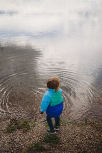 Back view of male child looking at the water of a lake in a park