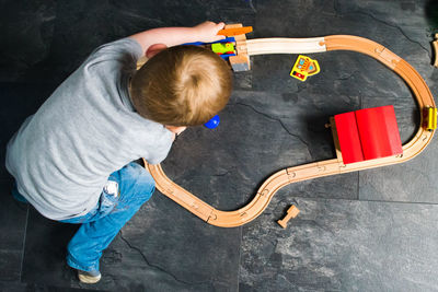 High angle view of boy playing with miniature train at home