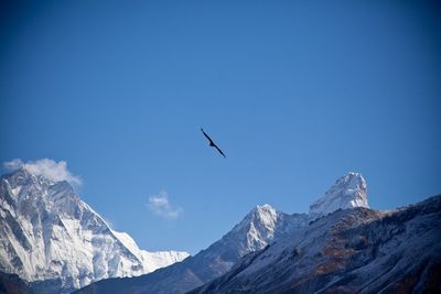 Low angle view of snowcapped mountains against clear blue sky