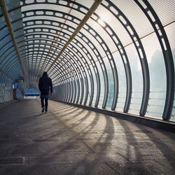 Rear view of man walking on pedestrian walkway