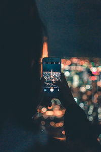 Man photographing illuminated smart phone at night