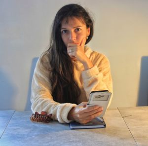 Portrait of young woman sitting on table at home