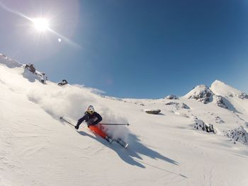 Man skiing on snowcapped mountain against sky