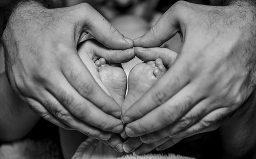 Cropped image of couple holding touching baby feet