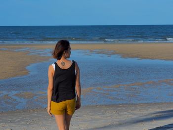 Rear view of woman standing on shore at beach