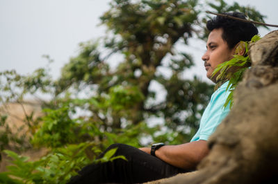Close-up of young woman against trees against sky