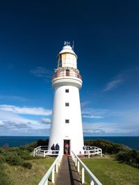 Lighthouse by sea against blue sky