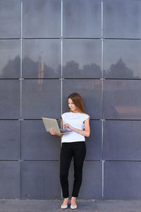 Full length of woman standing against wall