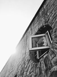 Low angle view of house mounted on wall against clear sky