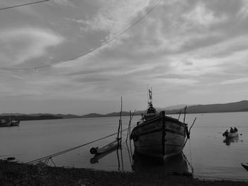 Fishing boats moored on sea against sky
