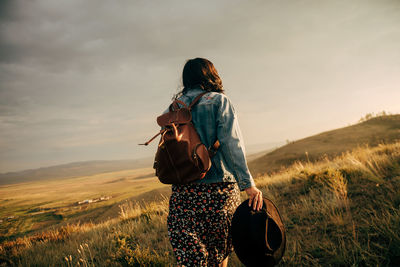 Rear view of woman standing on field against sky