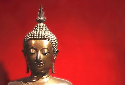 Statue of buddha against red wall