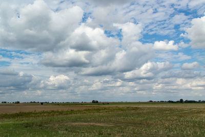 Scenic view of grassy field against cloudy sky