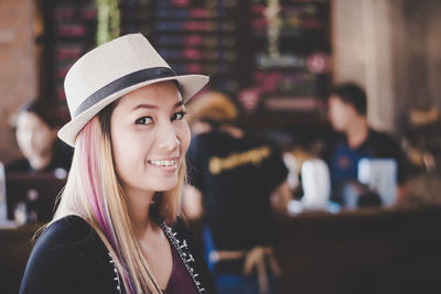 Portrait of smiling mid adult woman wearing hat in restaurant