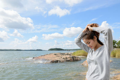 Woman standing at beach against sky