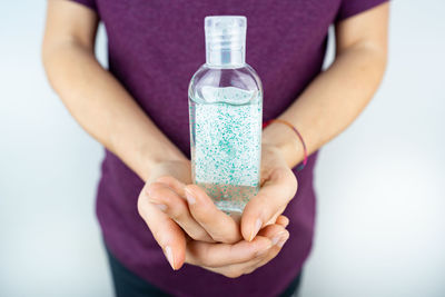 Midsection of woman holding purple against white background