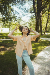 Happy woman standing by tree on field