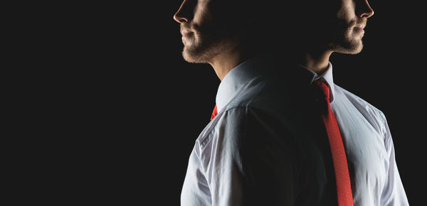 Young man standing against black background