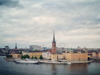 View of buildings at waterfront against cloudy sky