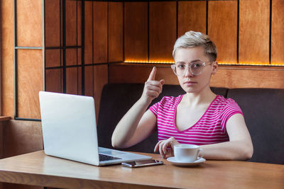 Young woman using phone while sitting on table