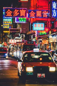 Cars on illuminated city street at night