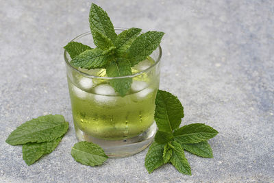 Green cool mint drink in front of concrete background