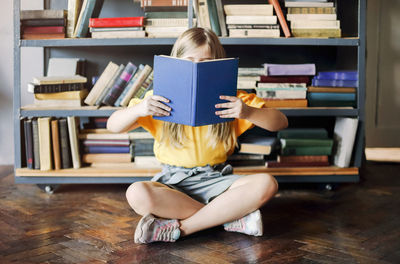 Midsection of woman reading book at home