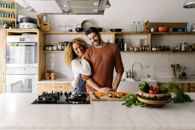 Woman standing by food in kitchen at home