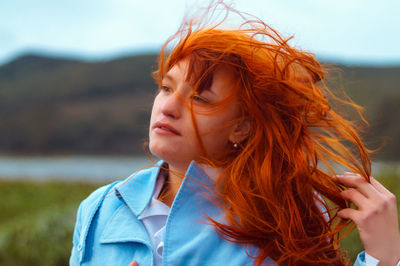 Close-up of young woman with tousled hair at lakeshore