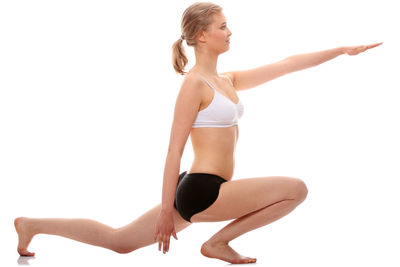 Young woman with arms raised against white background