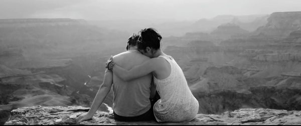 Rear view of couple sitting against mountains