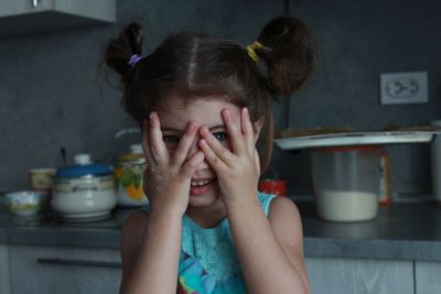 Smiling girl covering her eyes with hands