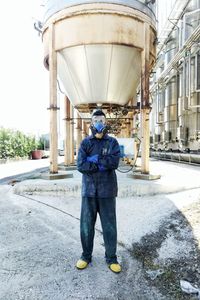 Full length portrait of man standing outside factory