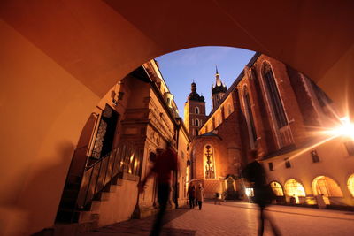 Blur image of people walking on street by tunnel against wawel cathedral at dusk