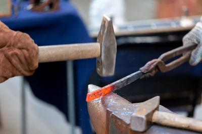 Cropped hand of blacksmith working at industry