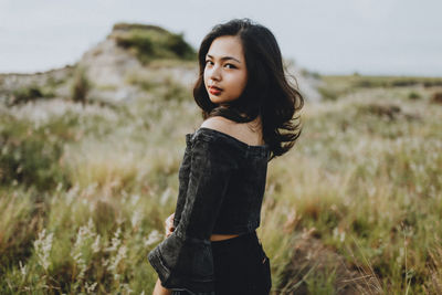 Beautiful young woman looking away while standing on land
