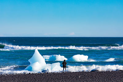 Rear view of woman standing at beach during winter