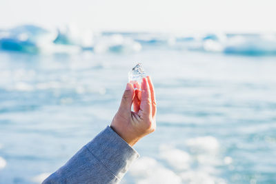 Cropped hand holding ice by glacier