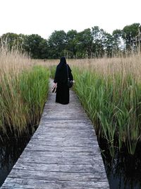 Rear view of woman walking in farm against clear sky
