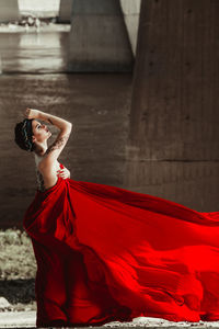 Side view of tattooed seductive fashion model with red fabric