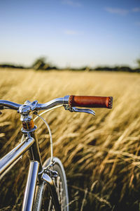 Bicycle on golden field against sky during sunset