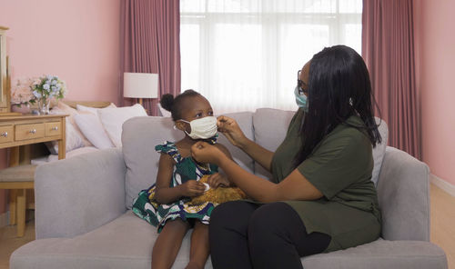 Mother wearing mask to daughter at home