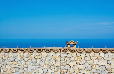 Built structure by sea against blue sky