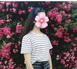 Midsection of woman standing by pink flowering plants