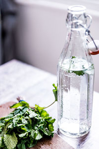 Close-up of water in bottle by mint leaves on table