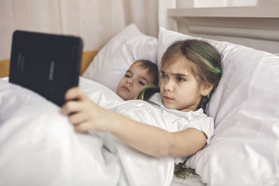 Siblings watching video in mobile devices in bed, gadget dependence and addiction, online lifestyle