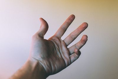 Cropped image of hand holding face over white background